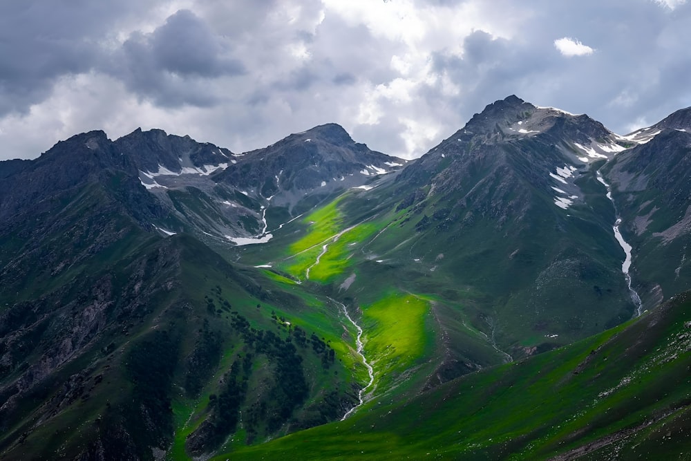 a view of a mountain range with green grass