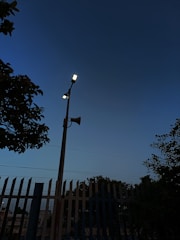 A bright solar-powered alarm mounted on a neighborhood streetlight at sunset.