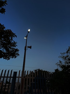 A bright solar-powered alarm mounted on a neighborhood streetlight at sunset.