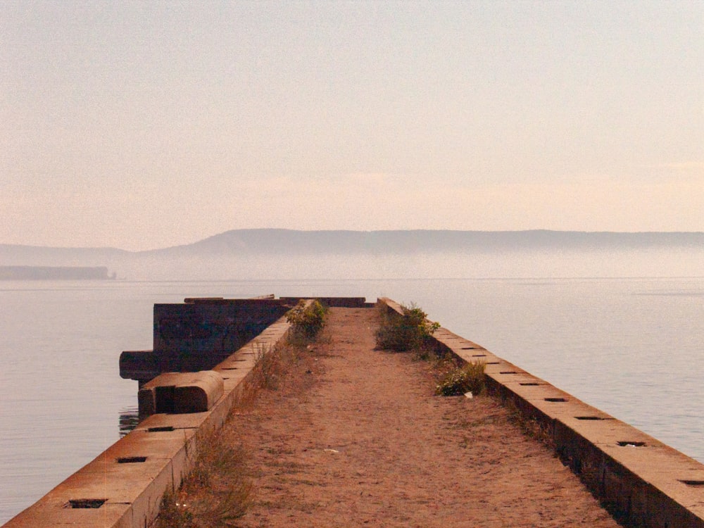 a bench sitting on the side of a pier next to a body of water
