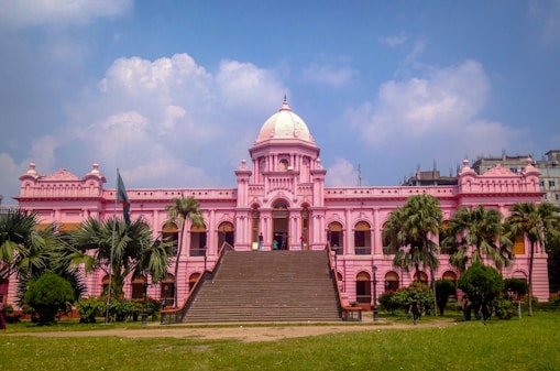 a large pink building with palm trees in front of it
