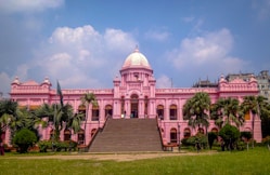 a large pink building with palm trees in front of it