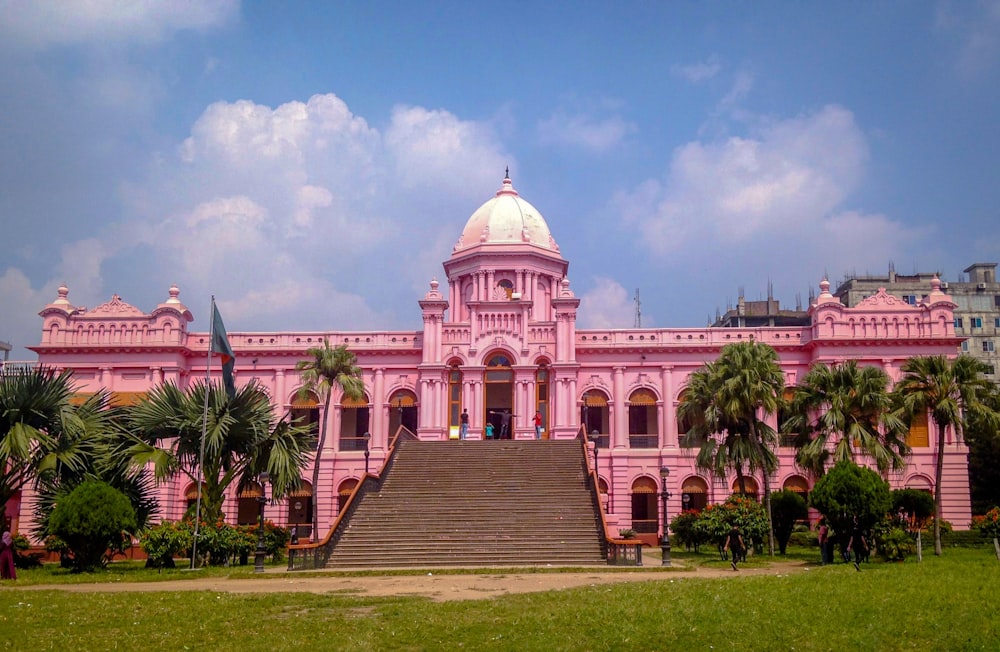 a large pink building with palm trees in front of it
