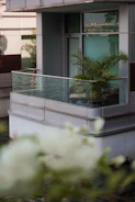 Modern balcony with sleek glass enclosure reflecting city skyline at sunset.