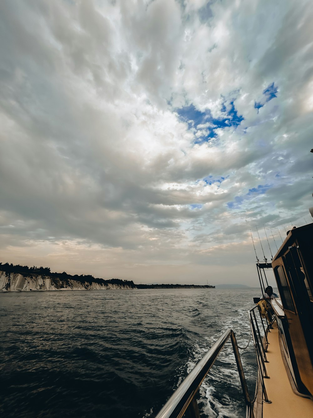 a boat traveling on a body of water under a cloudy sky