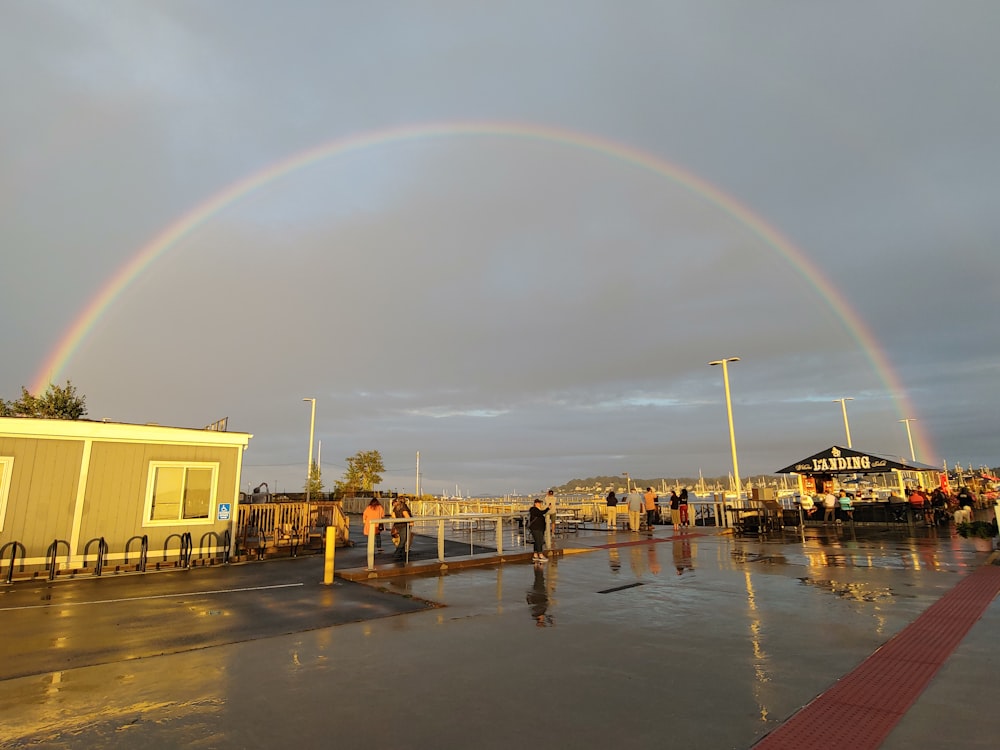 a rainbow appears over a parking lot as people walk by