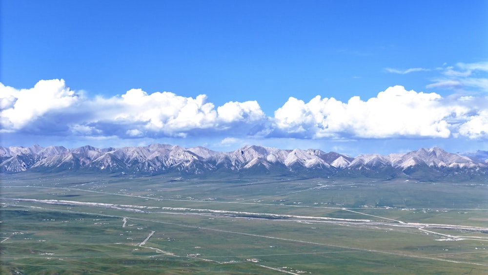 an aerial view of a mountain range with a road in the foreground