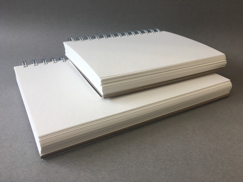 two spiral bound notebooks sitting on top of each other