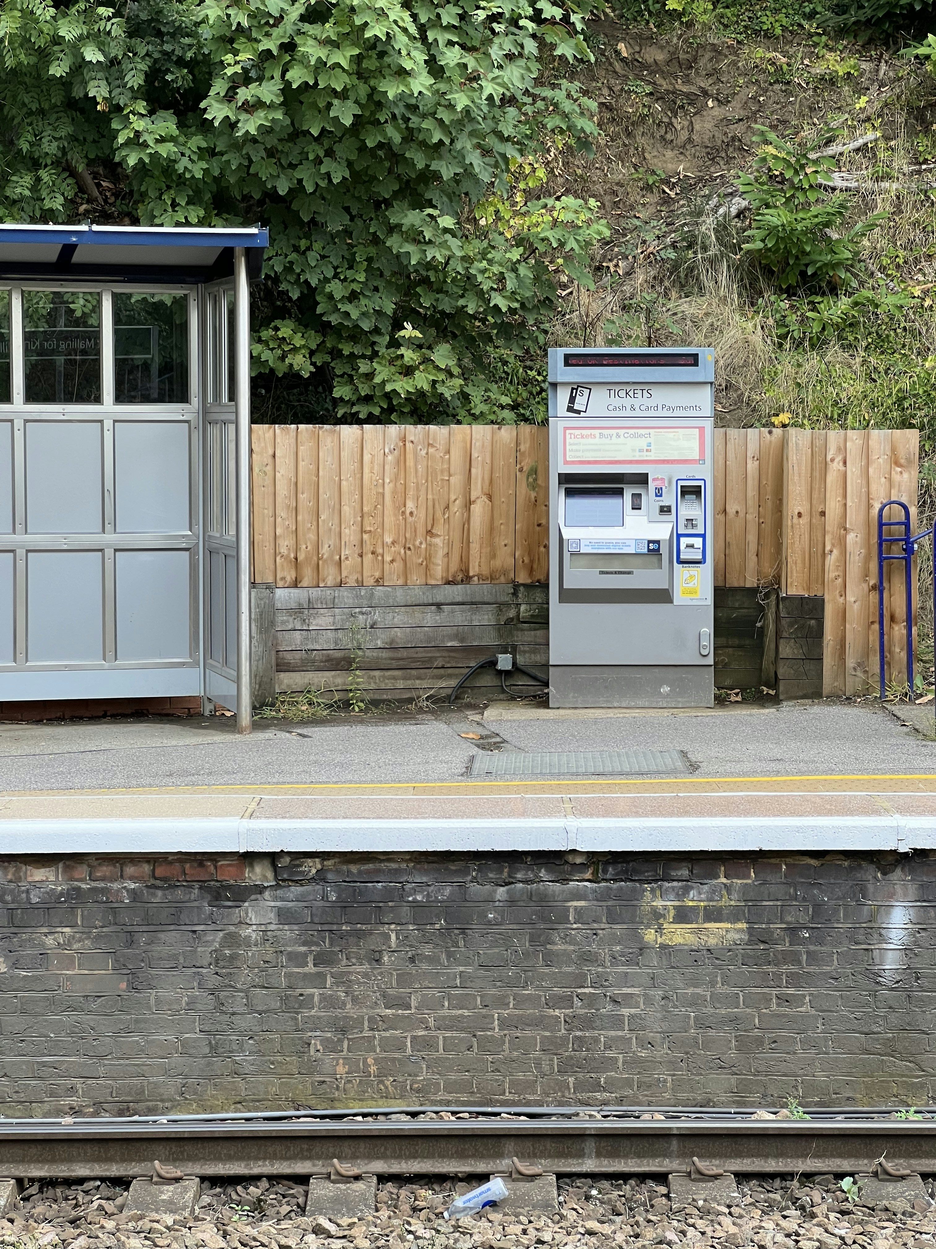 a parking meter sitting next to a wooden fence
