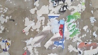 A weathered urban wall with faded graffiti and peeling posters, capturing the passage of time.