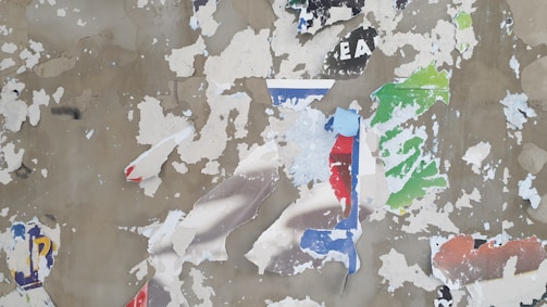 An intimate close-up of a weathered wall where layers of posters and graffiti overlap, telling stories of past interventions.