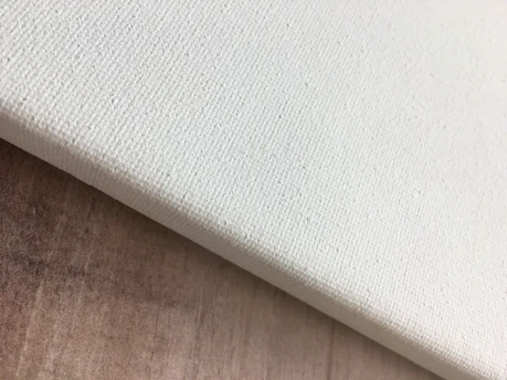 Close-up of a blank white canvas with subtle shadows in a cozy studio.