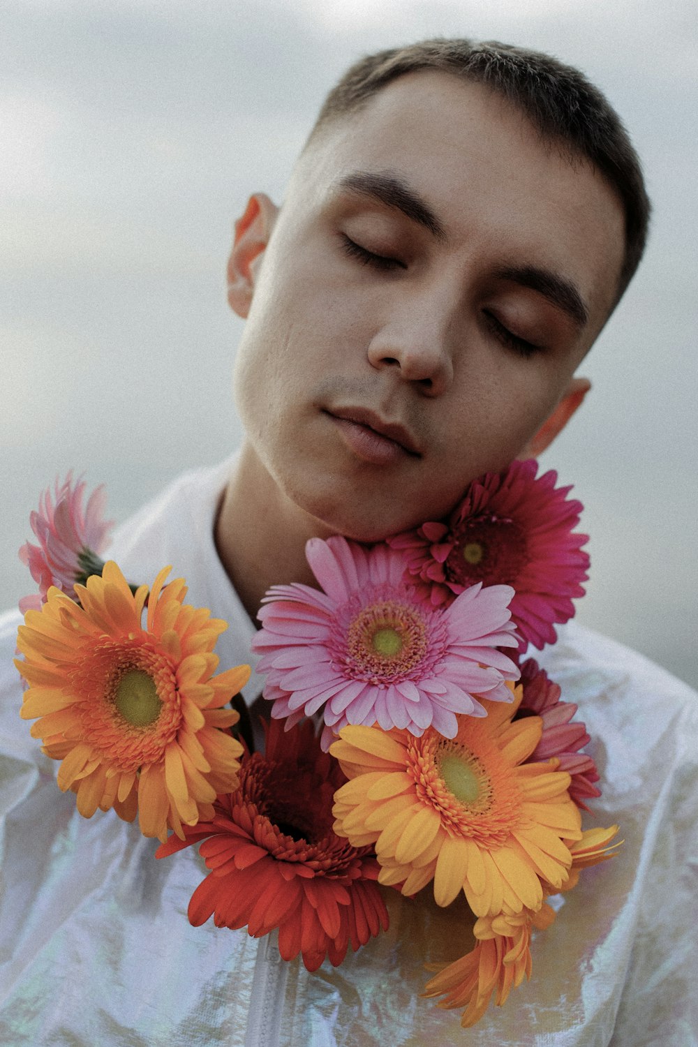 a man with his eyes closed holding a bunch of flowers