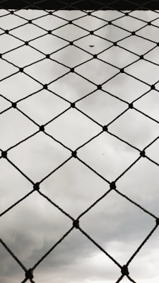 Installation process of diamond-shaped wire fencing in a residential area.