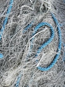 A chaotic tangle of ropes and nets, with strands interwoven in a complex pattern. Some ropes are thick and blue, contrasting with thinner, grayish-white netting.