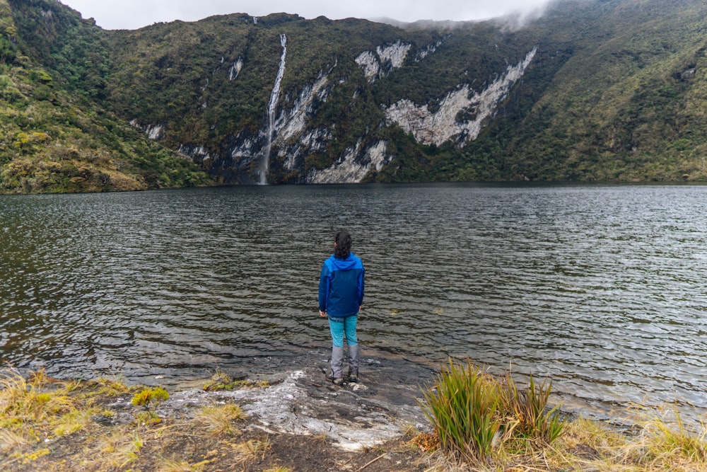 a person standing on a rock near a body of water