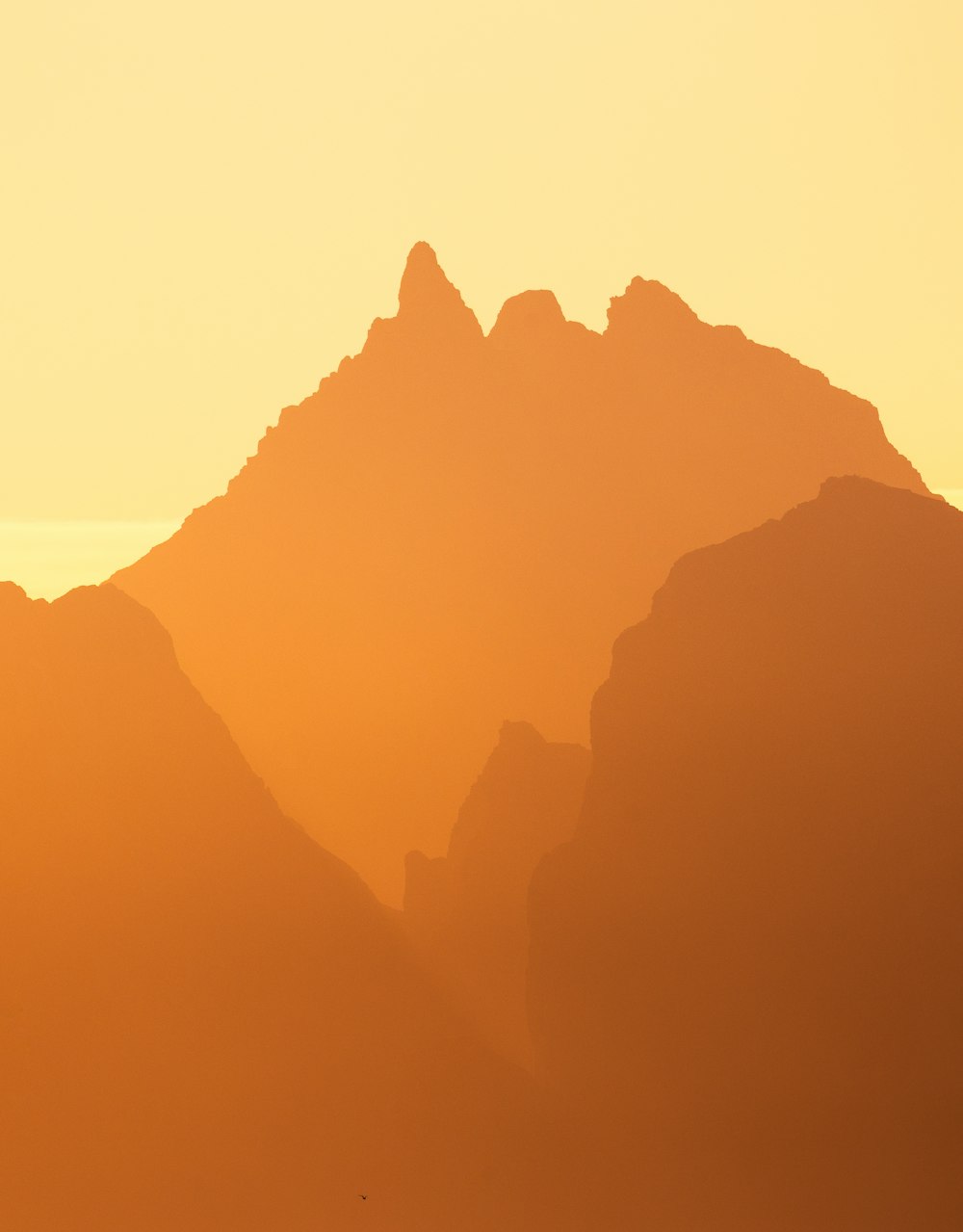 a plane flying over a mountain range at sunset