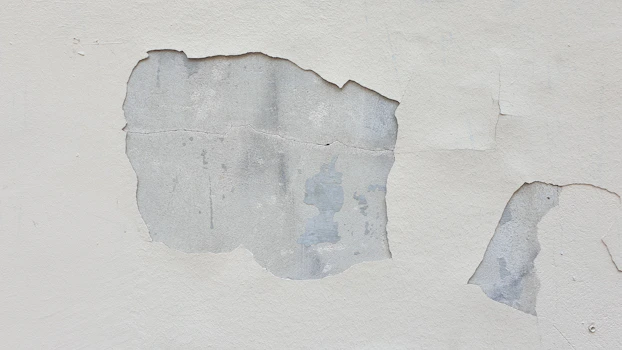 a close up of a white wall with peeling paint