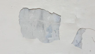 a close up of a white wall with peeling paint