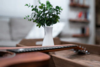 Close-up of a vintage acoustic guitar resting on a wooden table with sheet music scattered around.