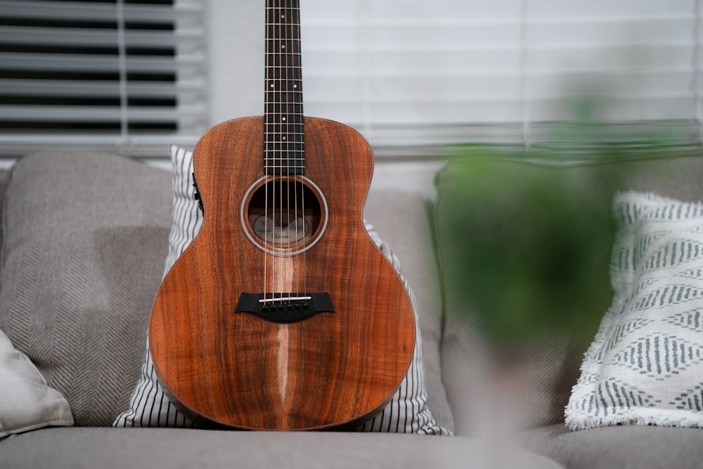 a guitar sitting on top of a couch next to a window