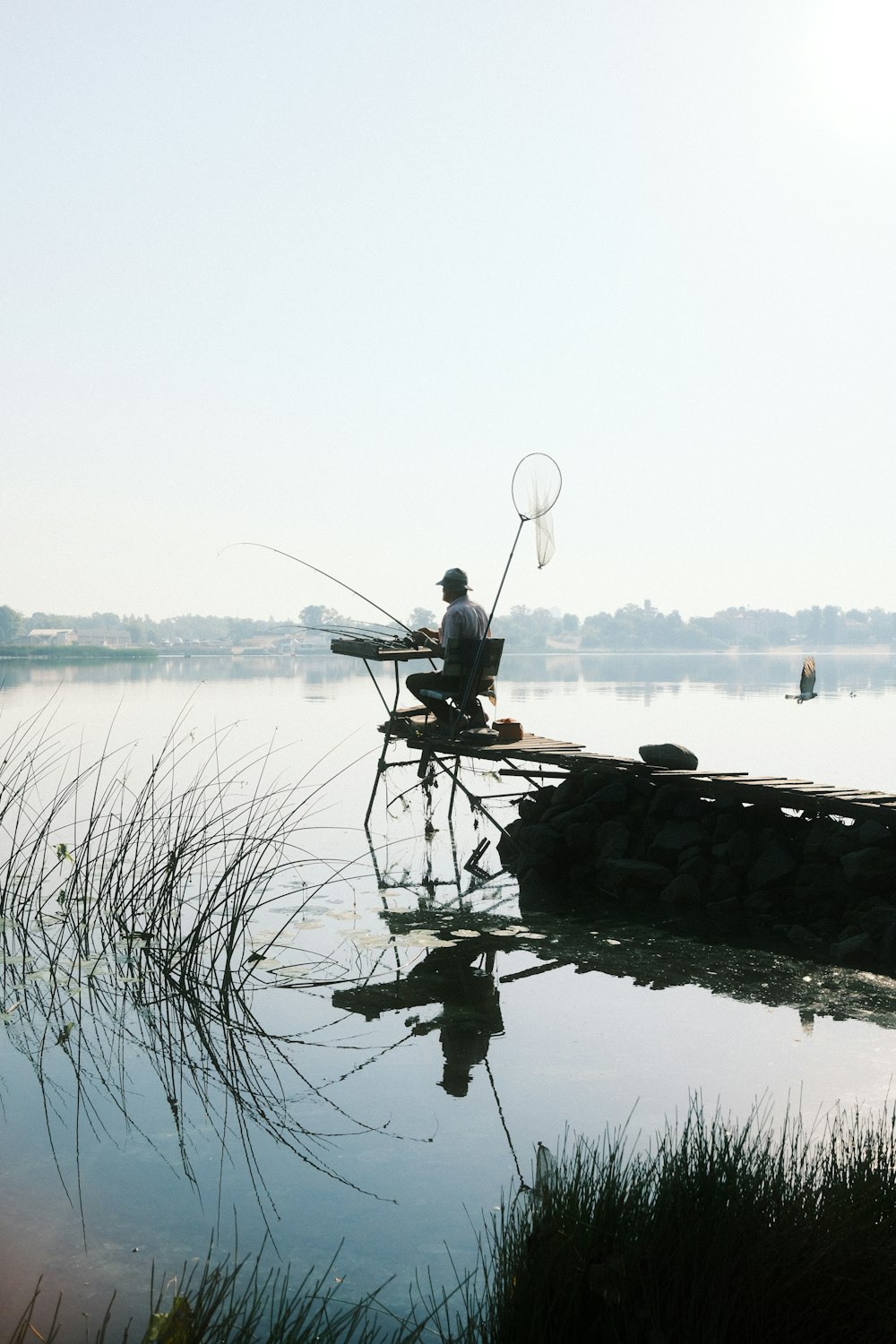 Un homme assis sur un quai avec une canne à pêche