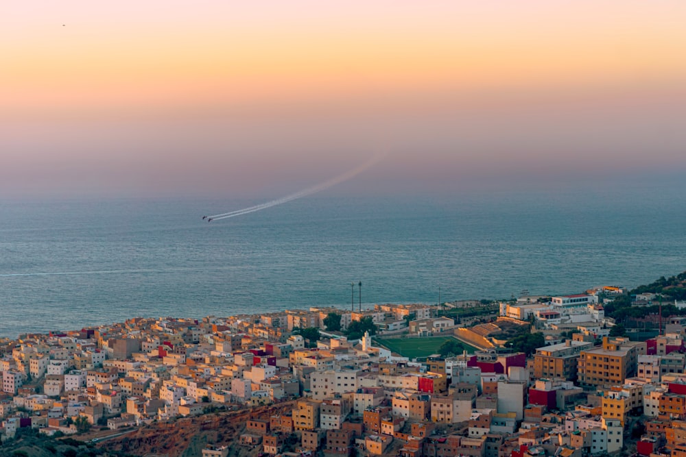 a view of a city and the ocean at sunset