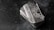 A stack of shiny rectangular silver bars with intricate designs and the inscription 'Scottsdale Mint'. The bars feature a depiction of a lion and have text indicating purity and weight, 'FINE Silver .999'. The background is a dark textured surface, providing contrast to the reflective nature of the bars.