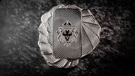 A stack of intricately designed rectangular silver bars with a lion's head wearing a crown engraved in the center. The bars have a textured pattern resembling a spiral, creating an elegant and regal appearance. The background is a dark, marbled surface that enhances the metallic shine of the bars.