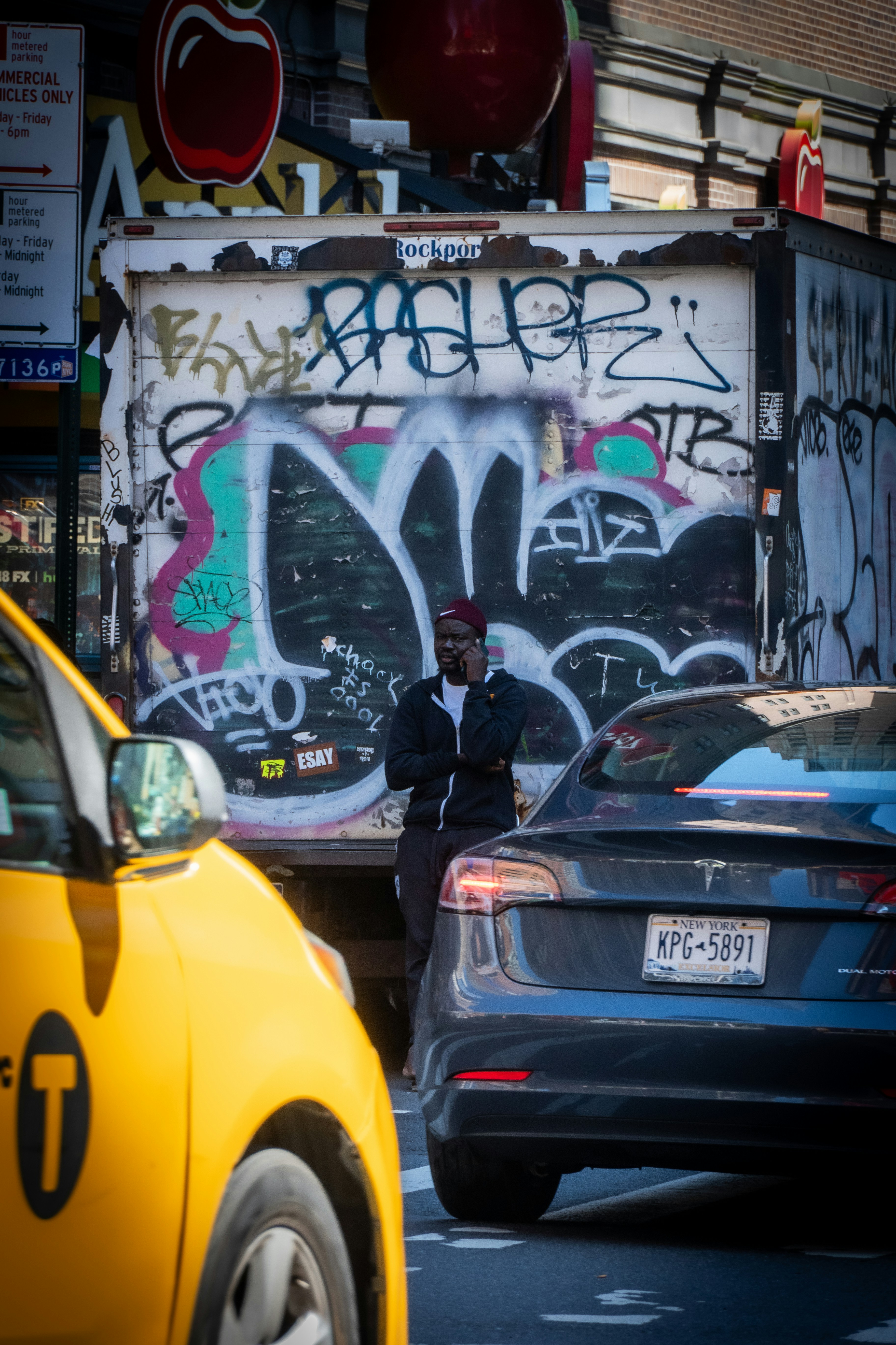 a man standing on the side of a road next to a yellow car