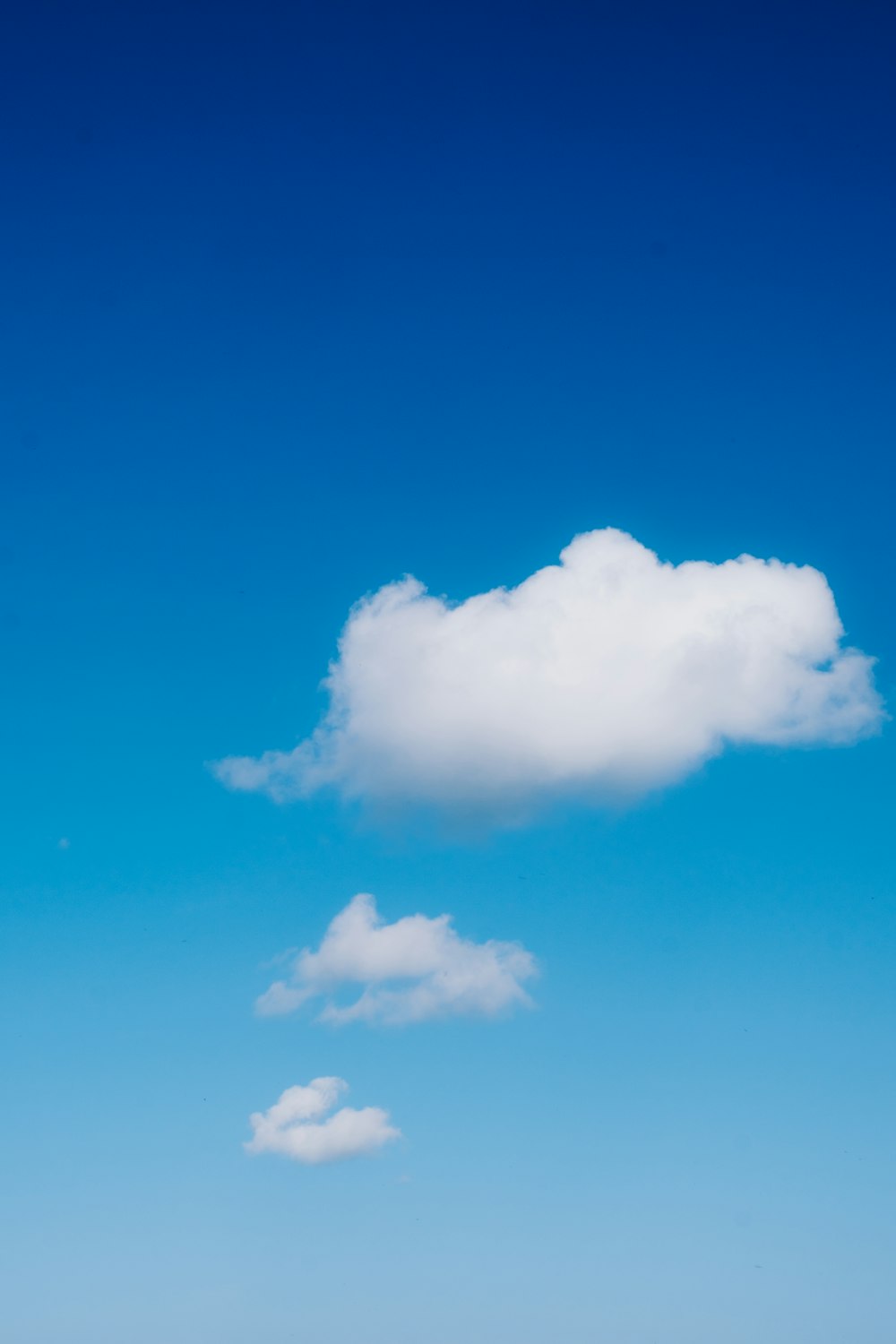 a lone cloud in a blue sky above a beach