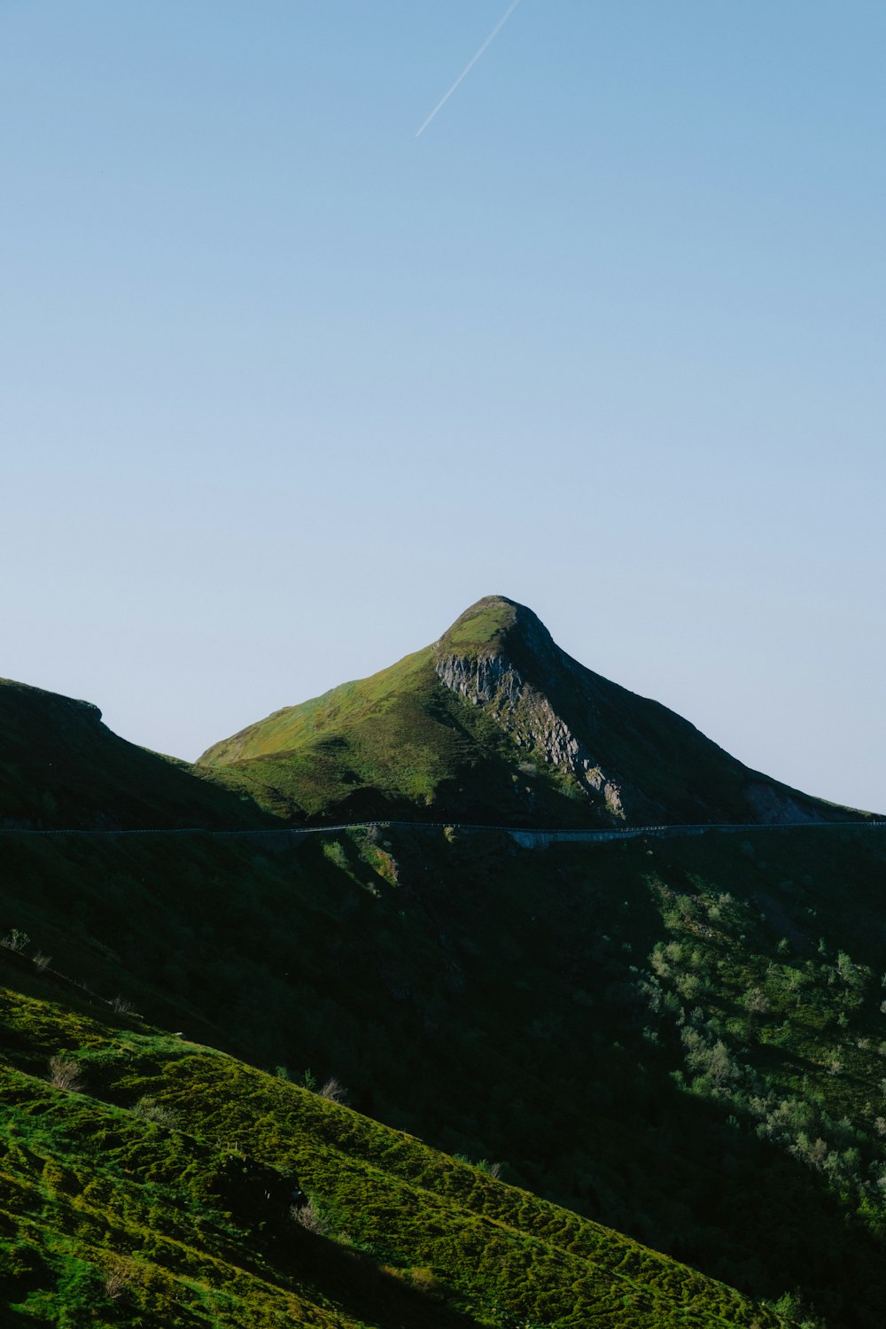 a view of a mountain with a plane flying in the sky