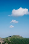 A mountain landscape with hiking trails and lush greenery under a clear sky.