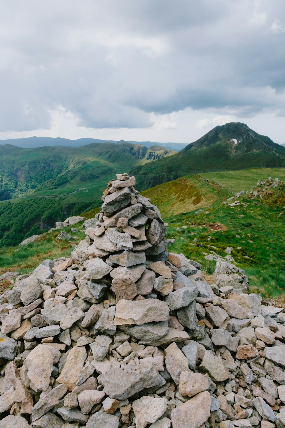 a pile of rocks sitting on top of a lush green hillside