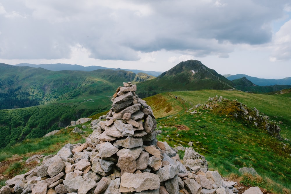 a pile of rocks sitting on top of a lush green hillside