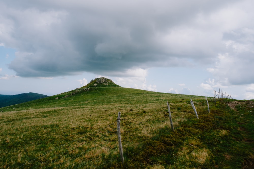 a grassy hill with a fence on top of it