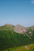 A scenic view of lush green mountains under a bright blue sky, inviting adventure.