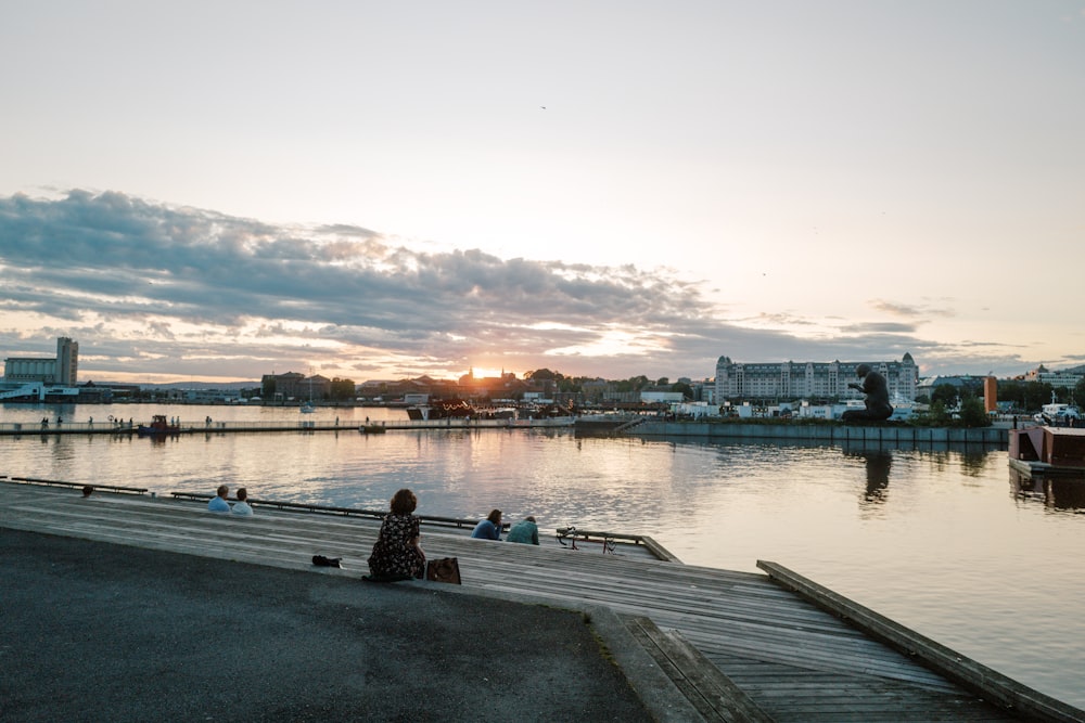 a woman sitting on a dock watching the sunset
