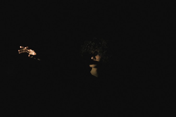 Person in a dark room holding a glowing phone screen