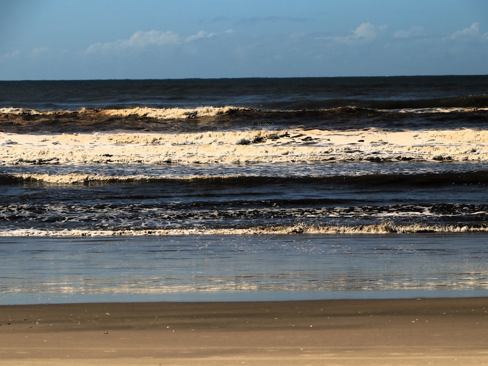 a person walking on the beach with a surfboard