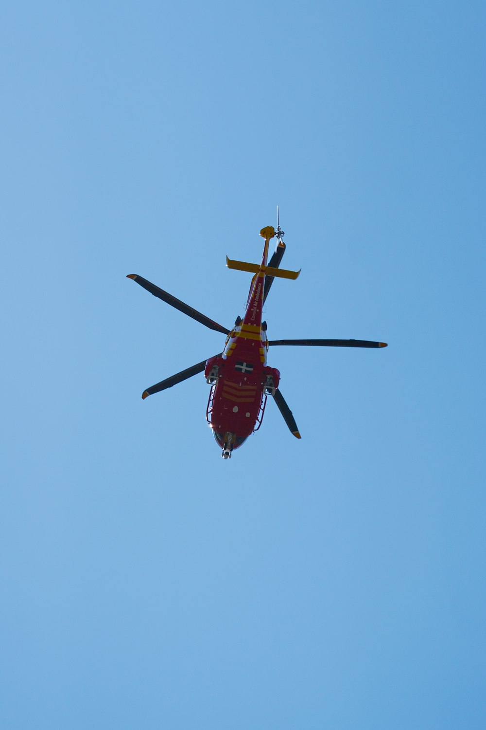 a red helicopter flying through a blue sky