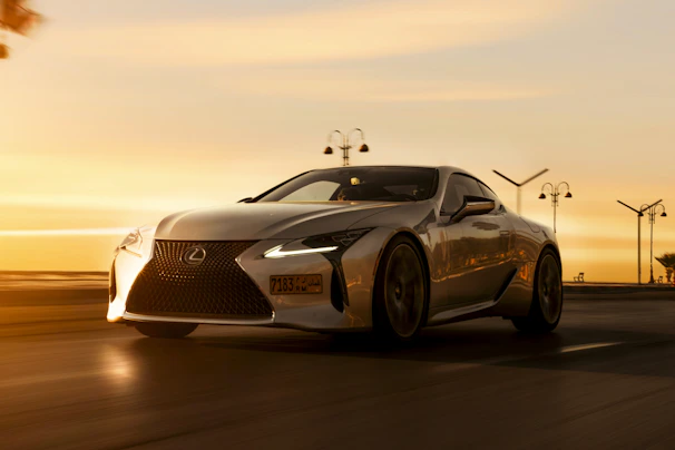 A shiny silver Lamborghini speeding along a palm-lined boulevard at dusk