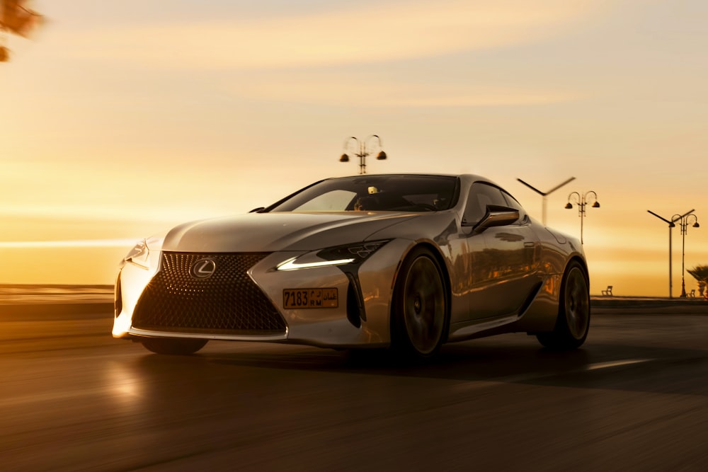 a silver sports car driving down a road