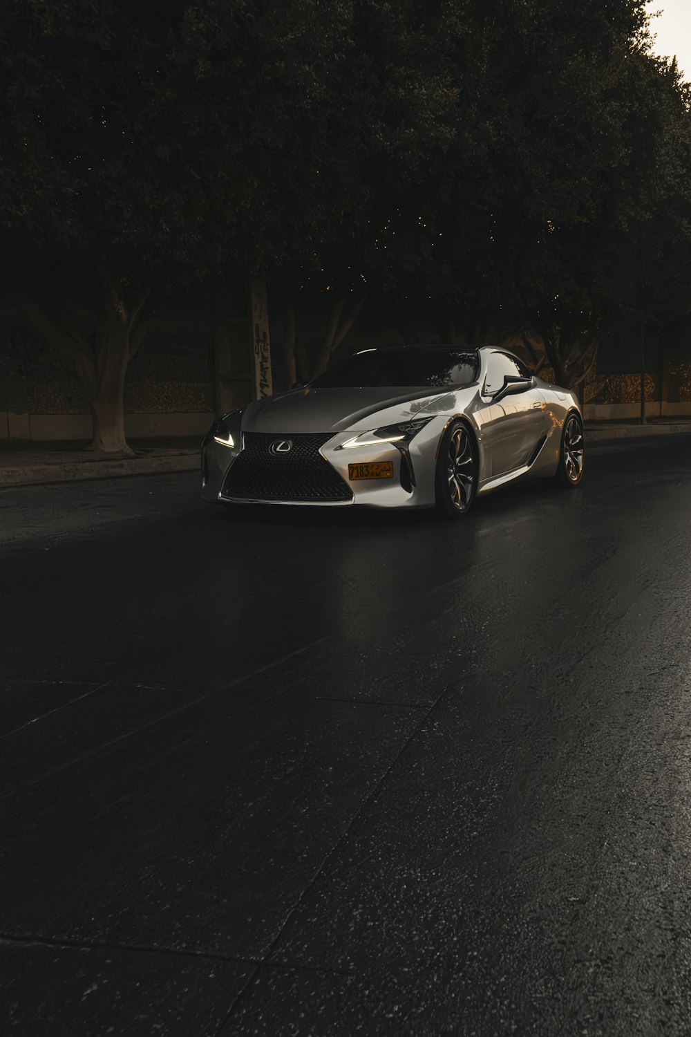 a silver sports car driving down a street at night