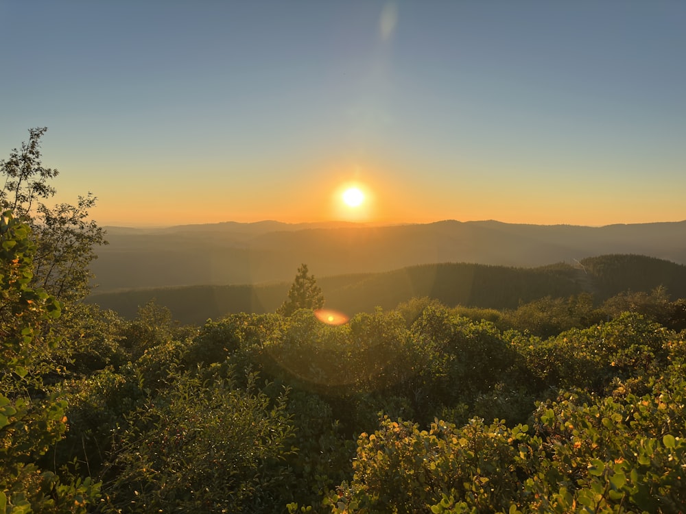 the sun is setting over the mountains in the distance