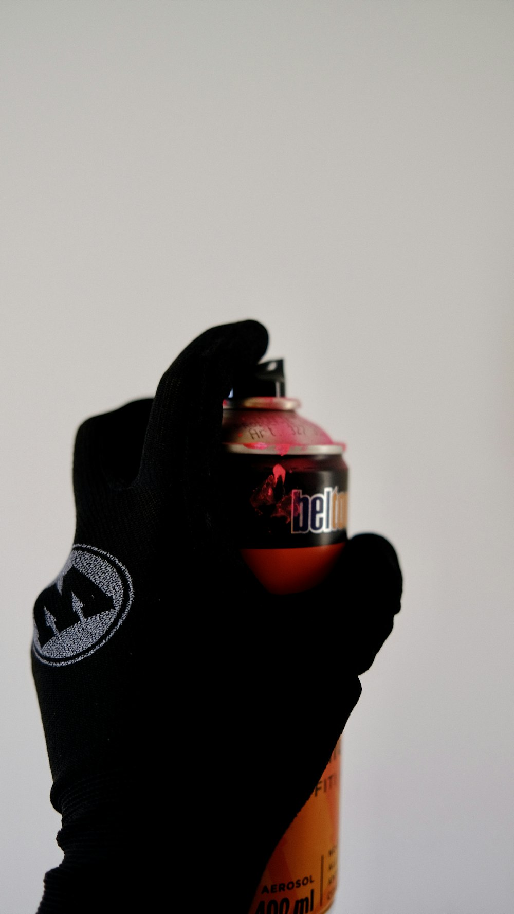a person wearing a black glove holding a can of beer