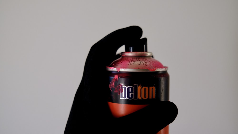a hand holding a red and black soda can
