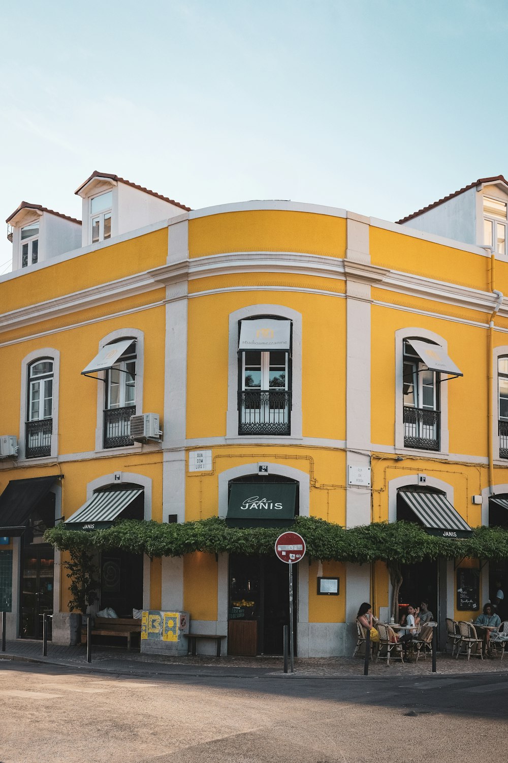 a yellow building with people sitting outside of it