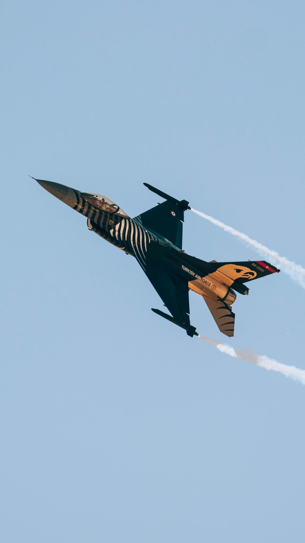 a fighter jet flying through a blue sky