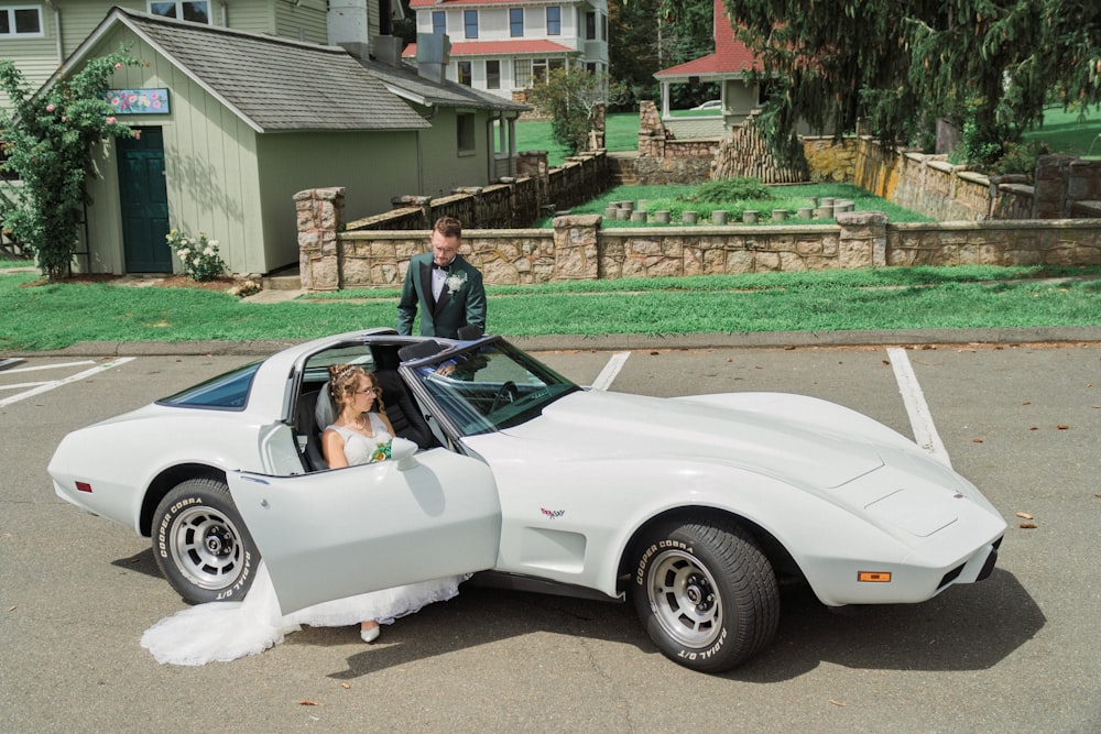 a bride and groom in a white sports car